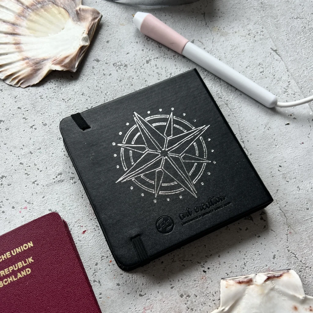 Live-Hot-Foiling-Activation-Compass-scaled schwarzes Skizzenbuch mit Silberfolie Hot Foiling Kompass live vor Ort in Düsseldorf personalisiert