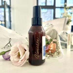 Flasche mit Gravur und Blumen im Hintergrund